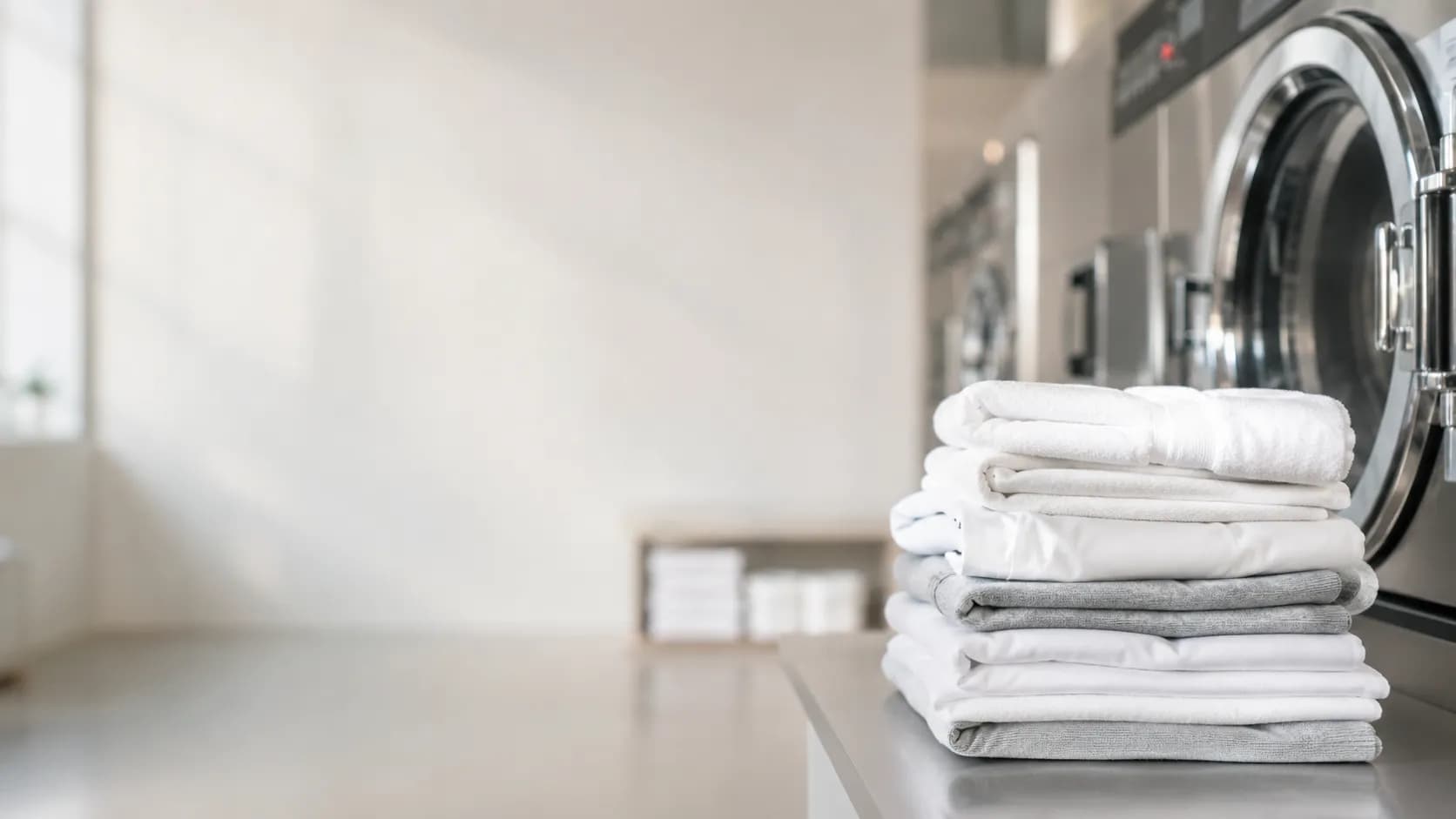 Neatly folded fresh white laundry in a bright Cardiff launderette